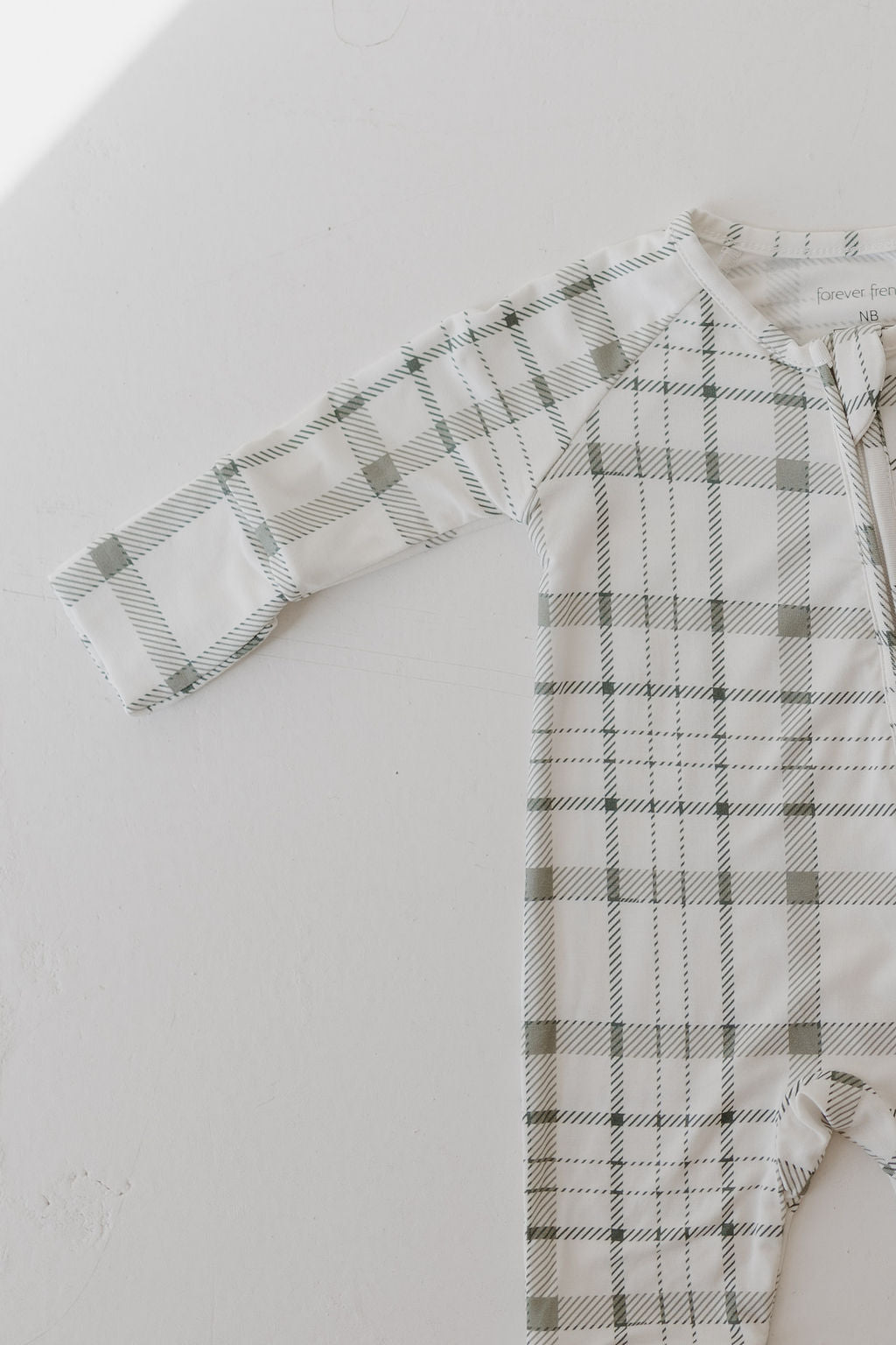 The Bamboo Zip Pajamas by forever french baby feature a comfortable and breathable hypoallergenic bamboo fabric with a charming green and white picnic plaid design. They're designed with long sleeves and a front tie closure for added comfort.