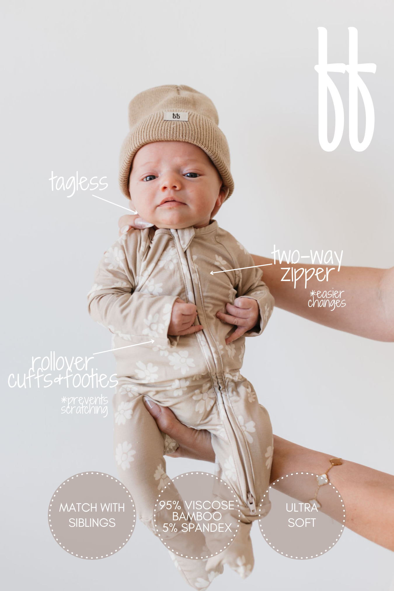 A baby wearing the "Bamboo Zip Pajamas | Lazy Daisy" by forever french baby, complete with a beige floral pattern and matching beanie, is held by adult hands. These bamboo pajamas are designed with tagless labels, a two-way zipper, rollover cuffs and footies, made of soft breathable fabric that blends viscose bamboo and spandex.