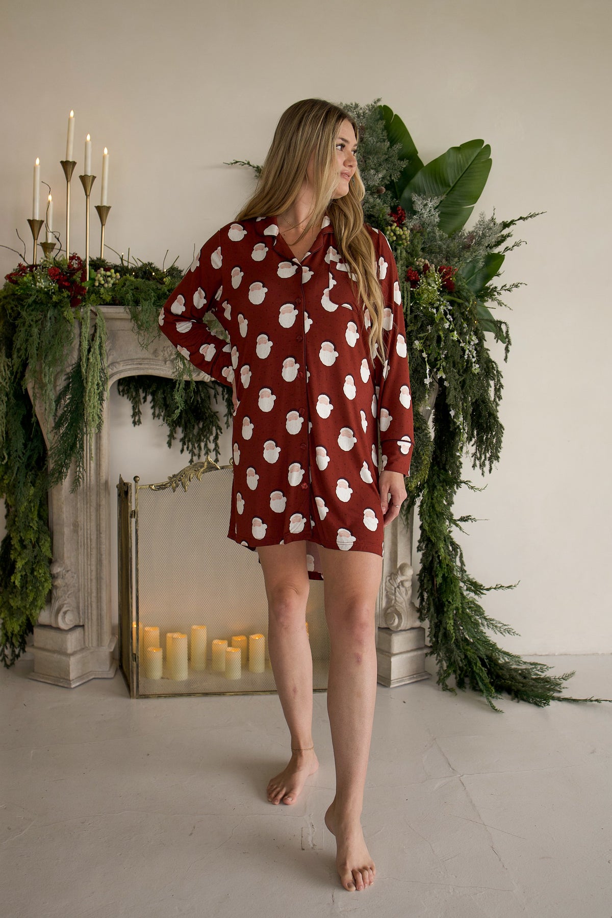 A woman wearing a Women’s Bamboo Sleeping Dress | Vintage Santa in deep red with a long-sleeved, button-up design and a vintage Santa Claus pattern.