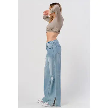 A woman wearing a beige long-sleeve crop top and I&M JEAN, INC.'s High Rise Skater Jeans in Medium Wash poses against a plain background.