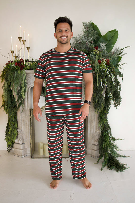 A man wearing Men’s Short Sleeve Pajamas | Holiday Stripe in a bamboo fabric with short sleeves and horizontal red, green, and white stripes.