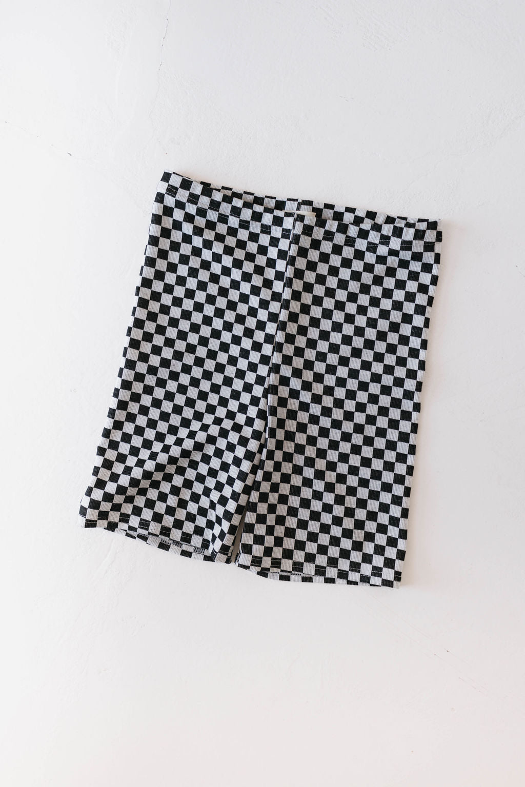 Children's Biker Shorts in black and white ribbed checker by forever french baby lie flat on a light surface. The shorts, designed for easy care with machine wash, are perfect for ages 0-9 years.