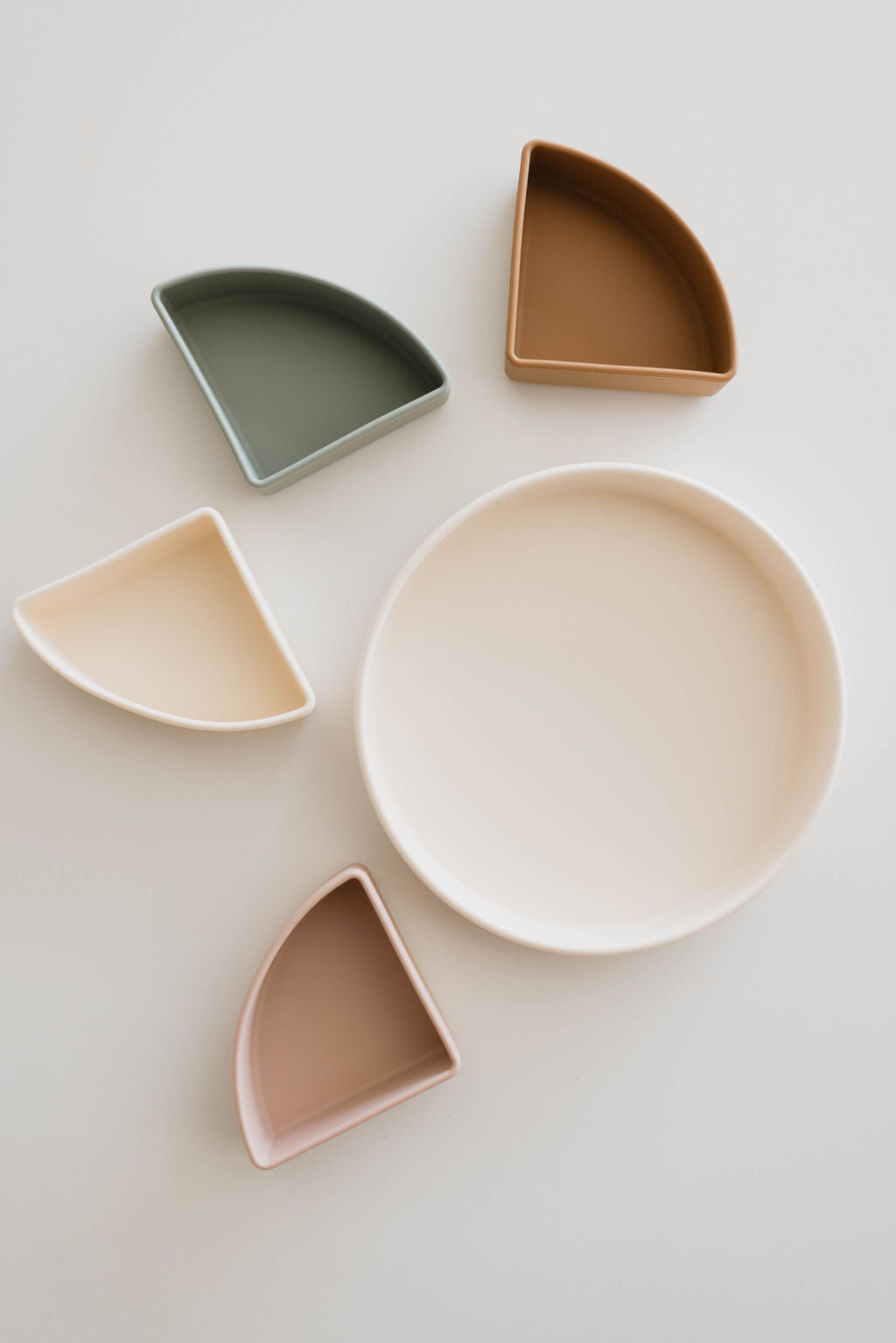 The Silicone Plate with Removable Dividers by forever french baby features a round, beige silicone plate surrounded by five smaller quarter-circle dishes in shades of green, brown, beige, pink, and cream. These neatly arranged dividers provide an organized mealtime experience.