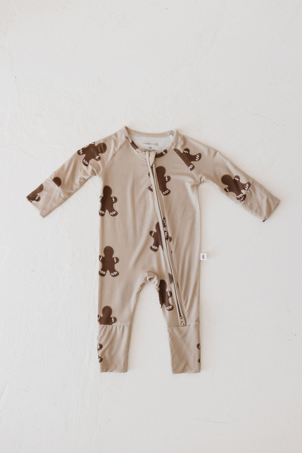 A Gingerbread Bamboo Zip Pajama from forever french baby, made of hypo-allergenic bamboo viscose, showcases adorable dark brown bear designs and a convenient front zipper. It is displayed on a light, textured surface.