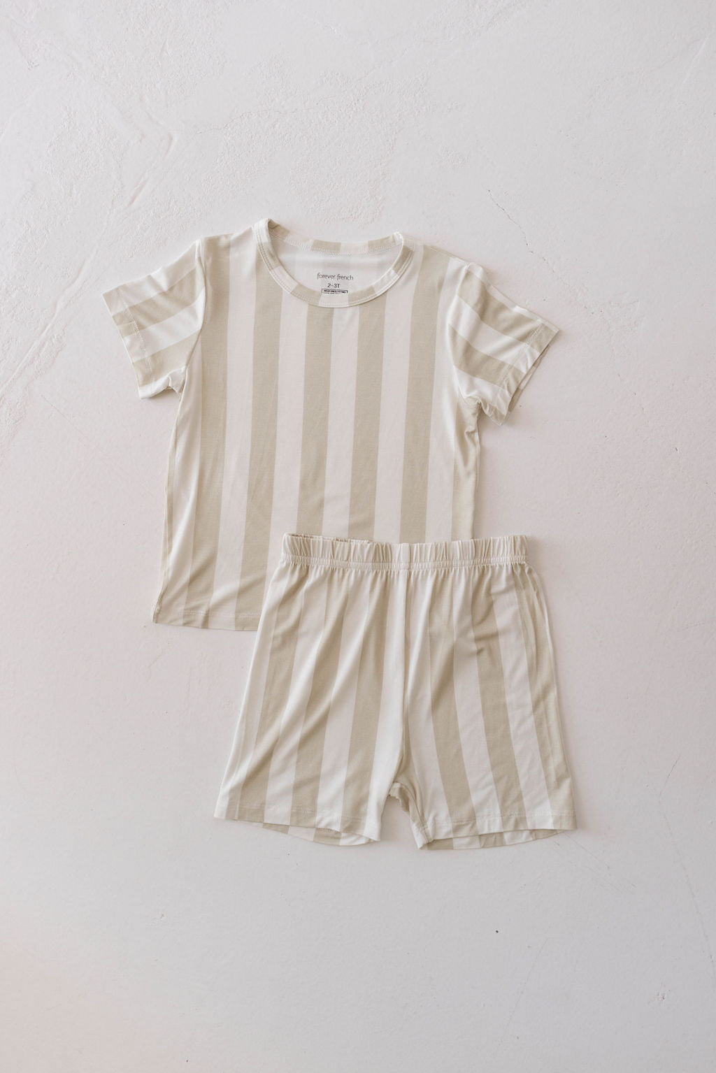 The Bamboo Short Set | Sand Stripe by forever french baby is shown laid flat on a white surface, featuring a beige and white horizontally striped short-sleeve shirt and matching shorts with an elastic waistband. Made from breathable baby wear fabric, this casual and comfy outfit set is perfect for your little one.