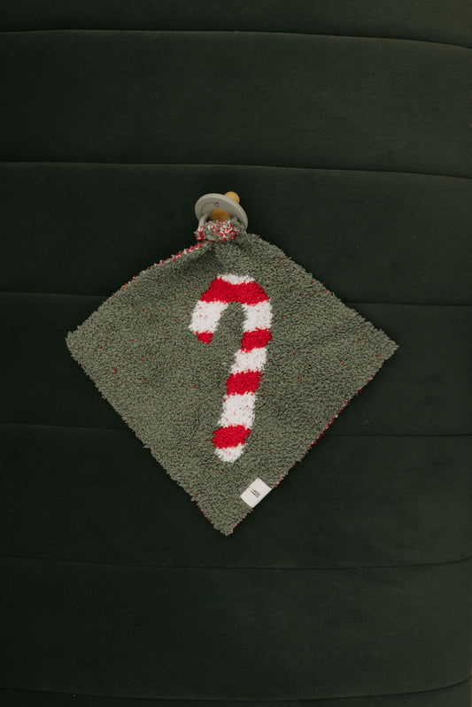 The Lovey | Candy Cane Lane by Forever French Baby is a luxurious, gray square cloth made from microfiber feather yarn. It showcases a red and white striped candy cane design attached to a pacifier, all set against a dark green background with vertical stitching. This elegant accessory is ideal for any Forever French Baby collection.