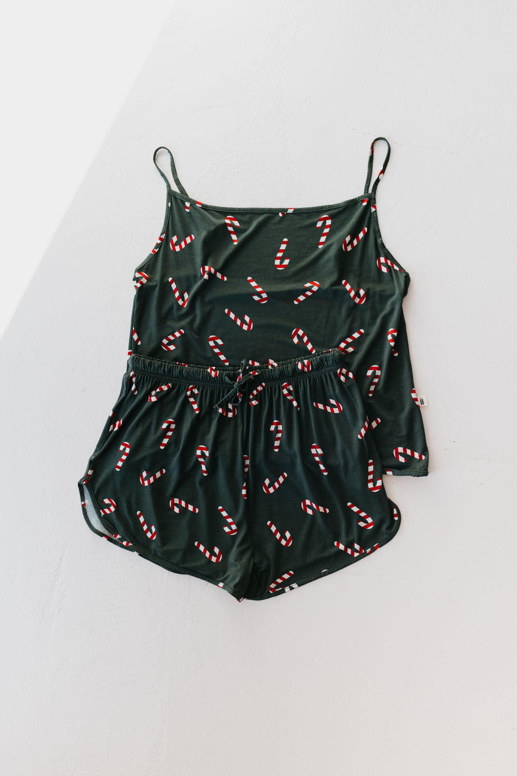 A Cami Women's Bamboo Set in a dark green hue adorned with red and white candy cane patterns is laid out flat on a light surface. Offered by forever french baby, this set features hypo-allergenic bamboo fabric that provides a cooling effect, complete with a drawstring waist and adjustable straps.
