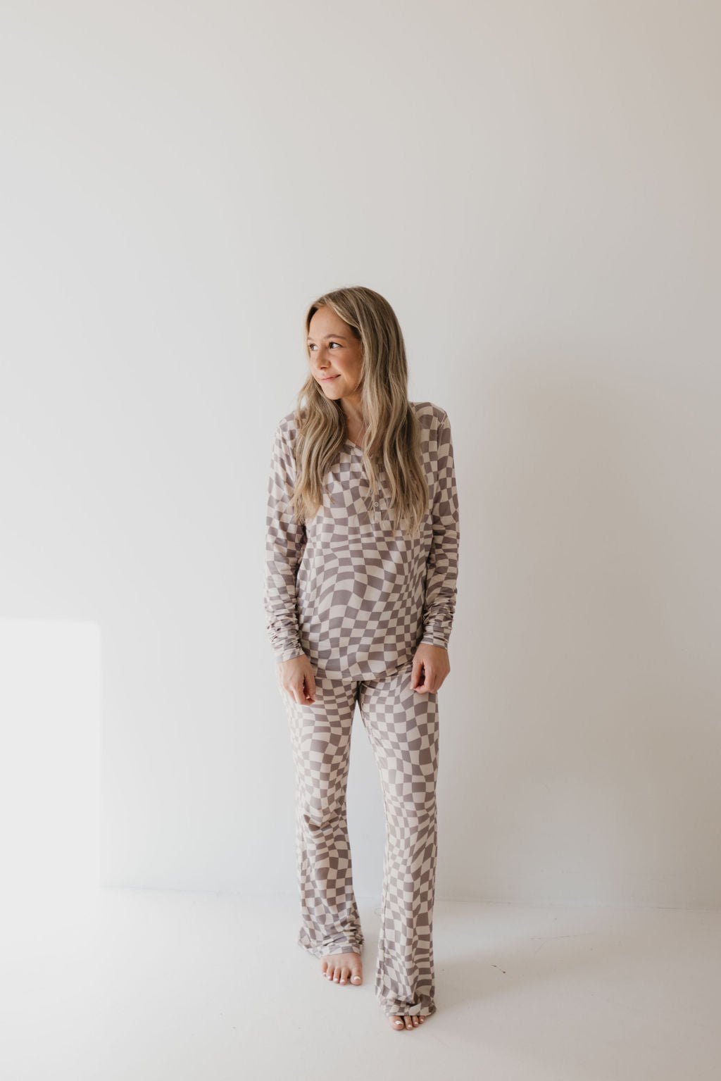 A person with long hair stands against a plain white background, dressed in the Smokey Wave women's bamboo pajamas from forever french baby. They are barefoot and looking to the side with a relaxed posture, perfectly embodying the essence of breathable clothing.