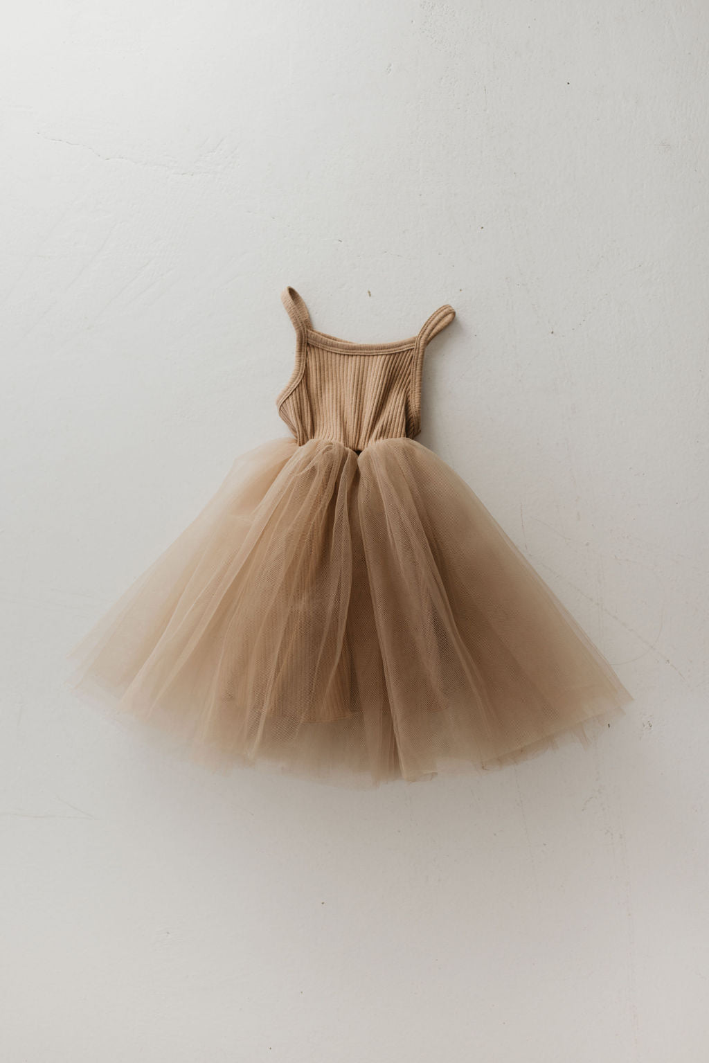 A petite, spice-colored tutu dress from forever french baby features a ribbed bodice and delicate tulle skirt, showcased against a white background as a versatile wardrobe essential.