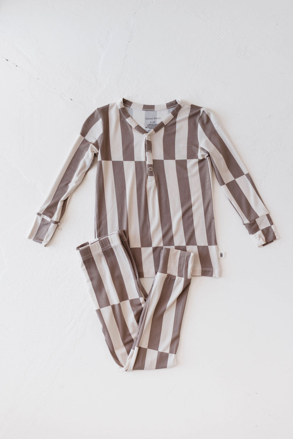 The Bamboo Two Piece Pajamas set, branded as Forever French Baby, includes a long-sleeved henley shirt and pajama pants with large vertical beige and brown stripes. The soft bamboo fabric features buttons at the neck and is neatly displayed on a clean, white background.