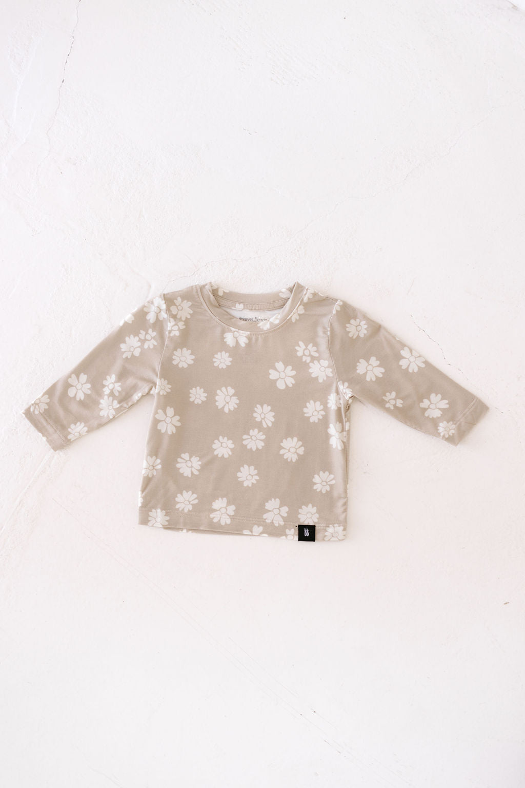 A forever french baby Long Sleeve Bamboo T-Shirt in beige, featuring a white floral pattern, laid flat on a white background.