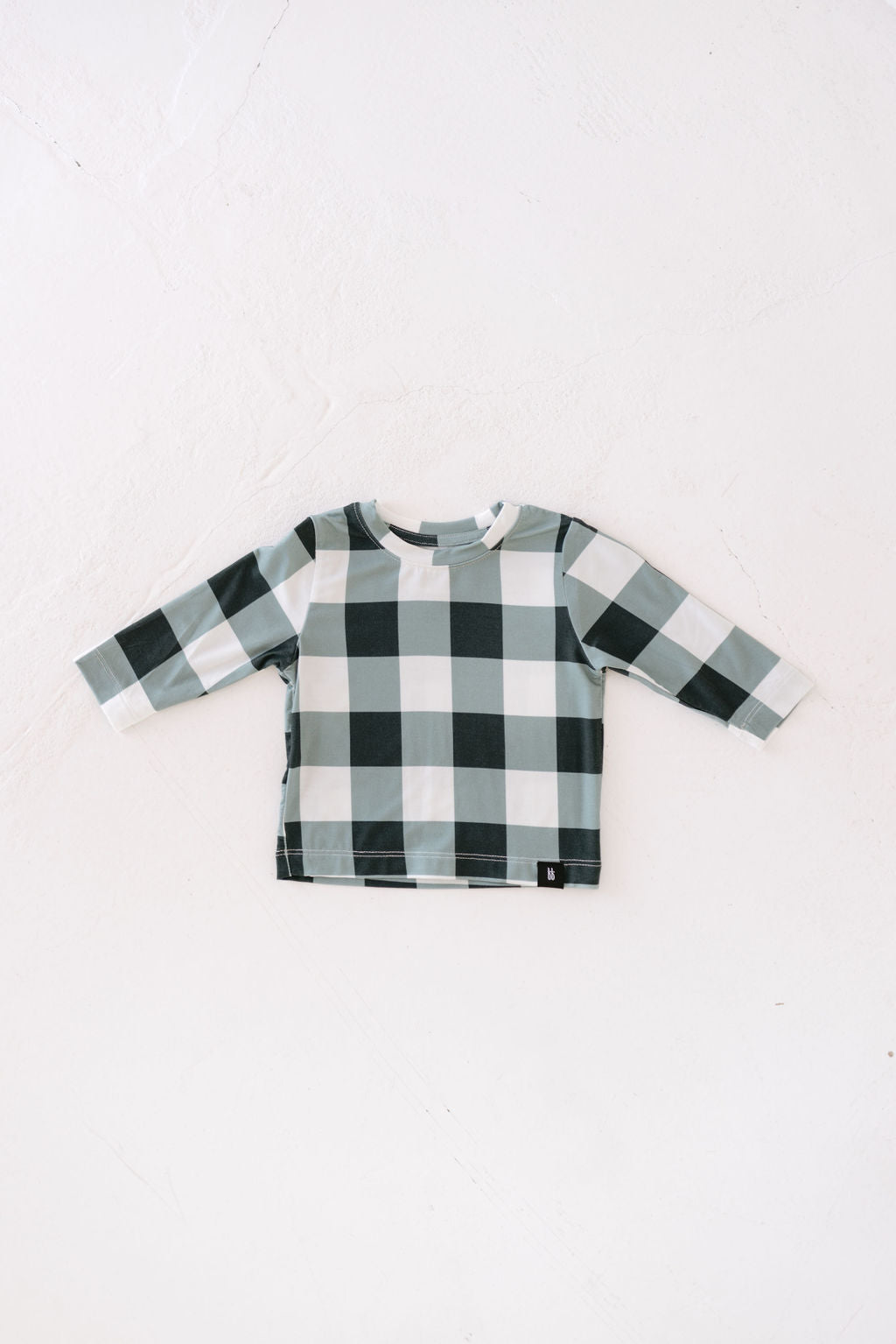 The "Bamboo Long Sleeve T-Shirt | Evergreen Gingham" from forever french baby is displayed on a white surface, highlighting its breathable bamboo fabric that feels gentle against the skin.