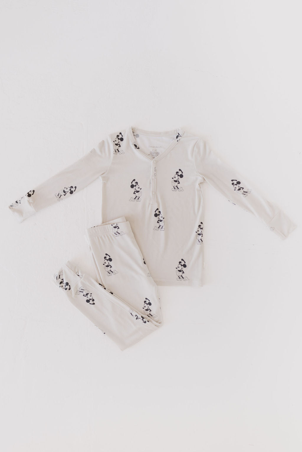 The Beige Bamboo Two Piece Pajamas featuring black and white dog illustrations by forever french baby include a button-up top and matching pants, all crafted from breathable bamboo fabric. The set is tastefully displayed on a plain white background.