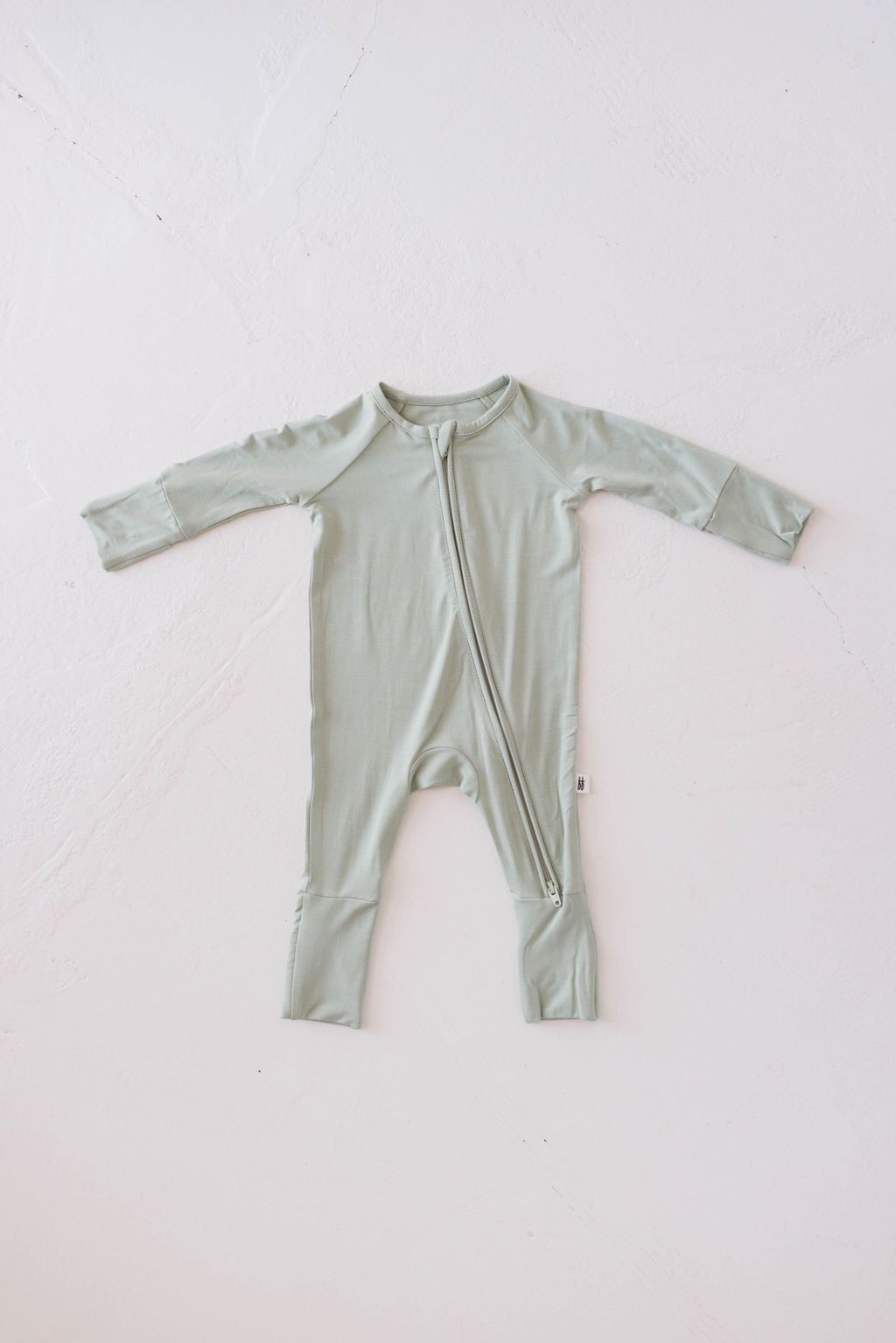 Displayed on a white background, the Bamboo Zip Pajamas in Pistachio from forever french baby showcase their long sleeves, central zipper, and covered feet. Made from premium bamboo, these hypo-allergenic onesies are laid flat to highlight their full shape.