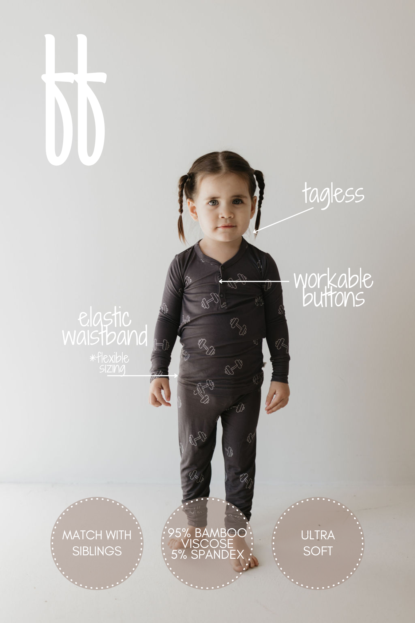 A young child is seen wearing a pair of "Arm Day" Bamboo Two Piece Pajamas by forever french baby. These pajamas feature dark, long sleeves with white illustrations and include an elastic waistband, functional buttons, and a tagless design for added comfort. Crafted from 95% bamboo viscose and 5% spandex, the breathable fabric offers ultra-soft comfort and adaptable sizing.