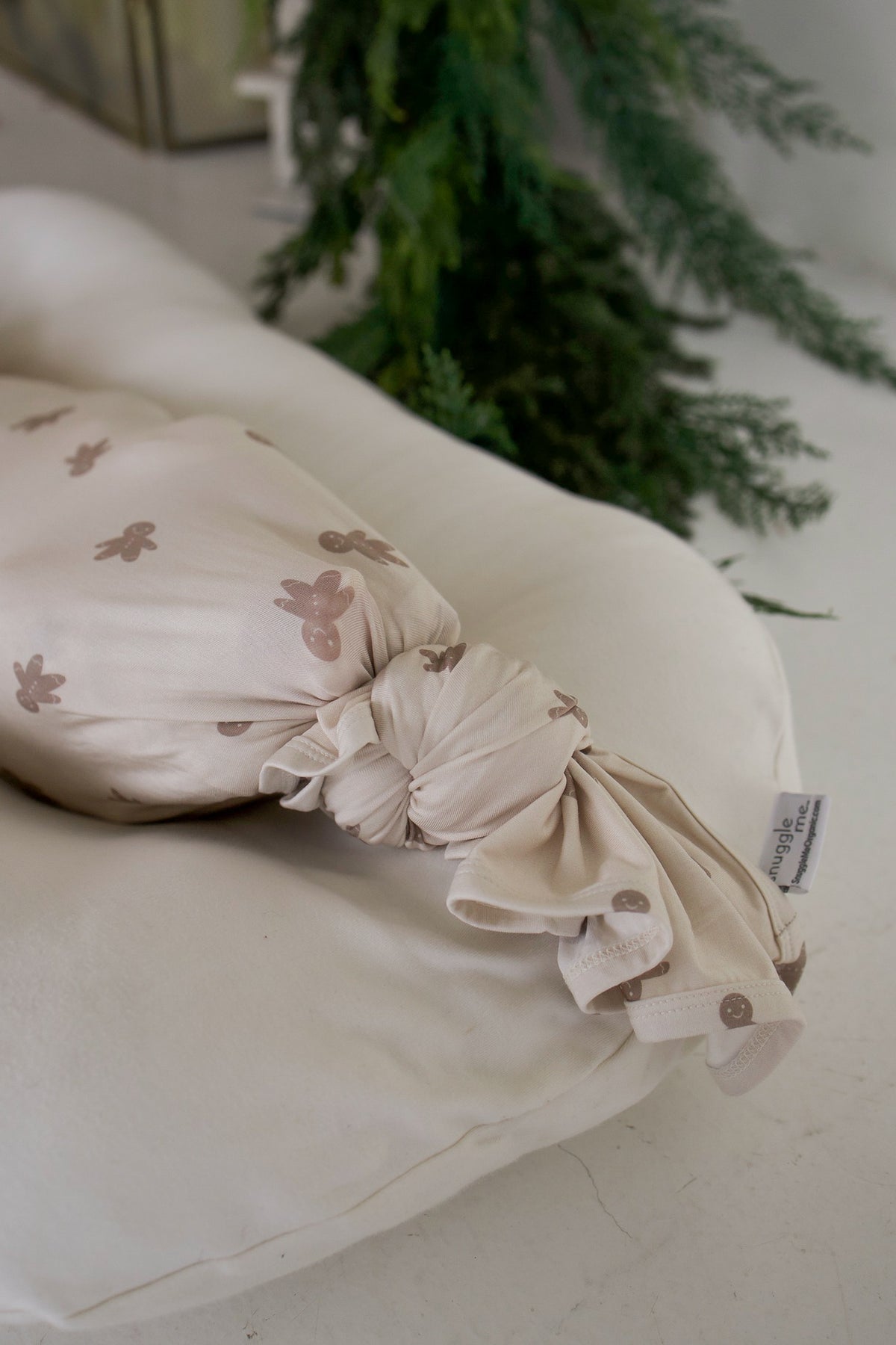 A swaddled infant wrapped in a Bamboo Swaddle | Gingersnap bamboo swaddle, resting on a white lounger.