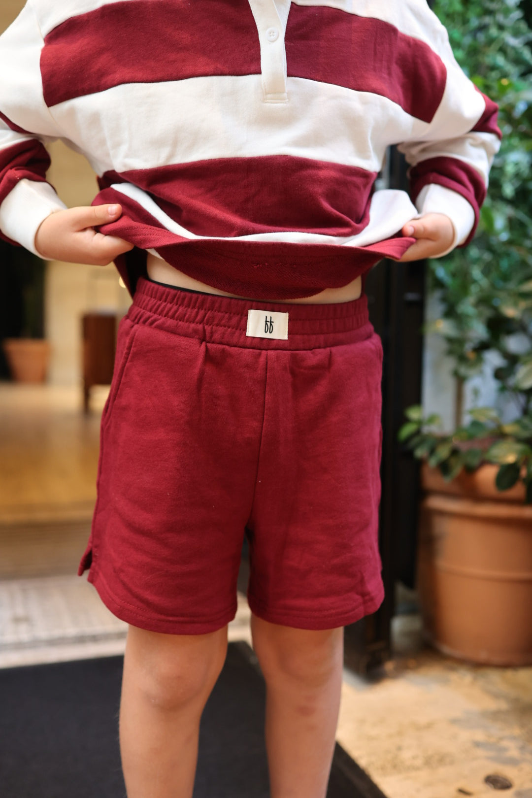 Deep Cranberry Child Terry Shorts in baby terry cloth featuring a small white brand tag at the center waistband.