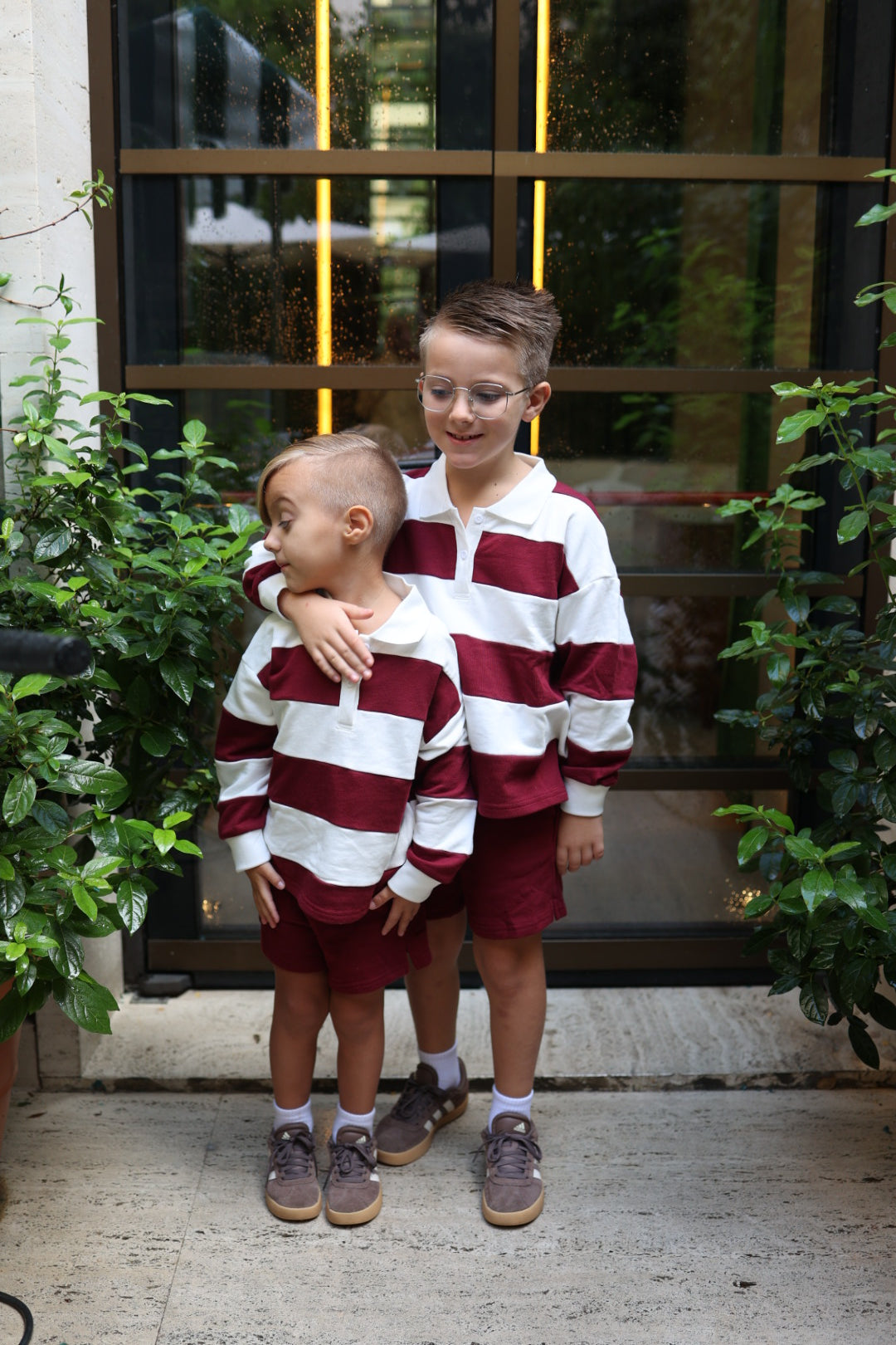 Two boys wearing matching Child Rugby Sweatshirt | Deep Cranberry sweatshirts in white and cranberry, paired with matching cranberry-colored shorts.