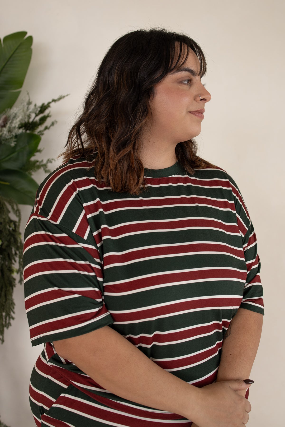 A person wearing a forever french baby Women’s Boxy Tee Lounge Set | Holiday Stripe, consisting of a short-sleeved crewneck t-shirt and matching bamboo shorts with a dark green, red, and white horizontal stripe pattern.