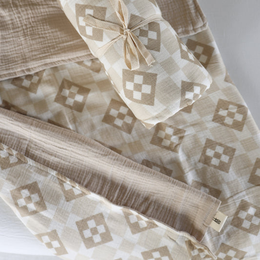 The forever french baby Muslin Quilt | Cottage Quilt in soft beige and white features a geometric diamond pattern and comes neatly folded with a matching swaddle—perfect for cozy, stylish baby nursery bedding.