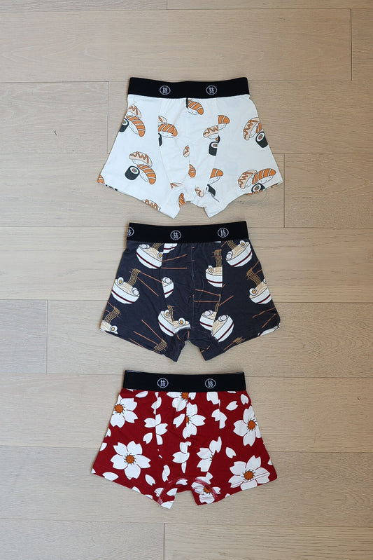 Three pairs of forever french baby Bamboo Boxers (Cherry Blossoms, Ramen & Sushi) are laid flat: one with sushi print, one with ramen bowls, and one with a white and yellow cherry blossom pattern.