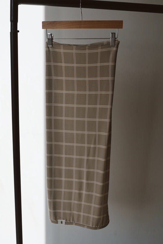 A Bamboo Swaddle in Linen Grid by forever french baby hangs neatly, its beige and white checkered design evoking the gentle comfort of a premium baby blanket.