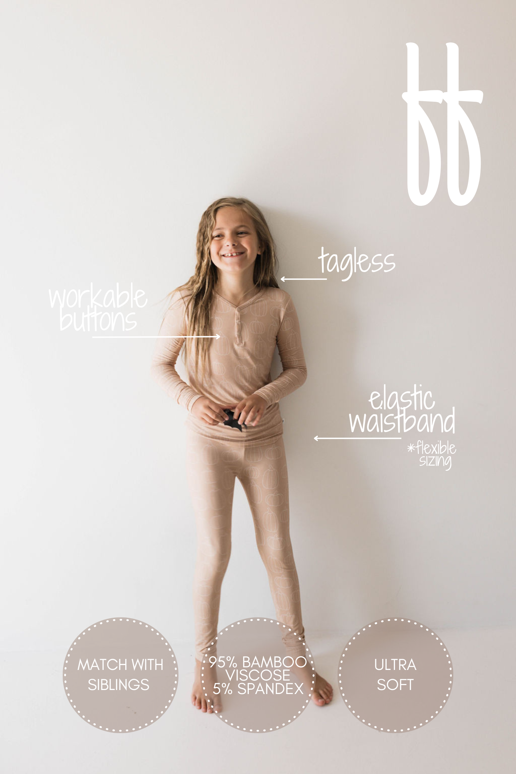 A young girl with long hair in light pink pajamas from Forever French Baby's Bamboo Two Piece Pajamas | Pumpkin Pie collection is smiling and standing against a plain white background. Labels on the image highlight features like workable buttons, a tagless design, an elastic waistband, and the fabric composition (95% hypo-allergenic bamboo viscose children's sleepwear, 5% spandex).