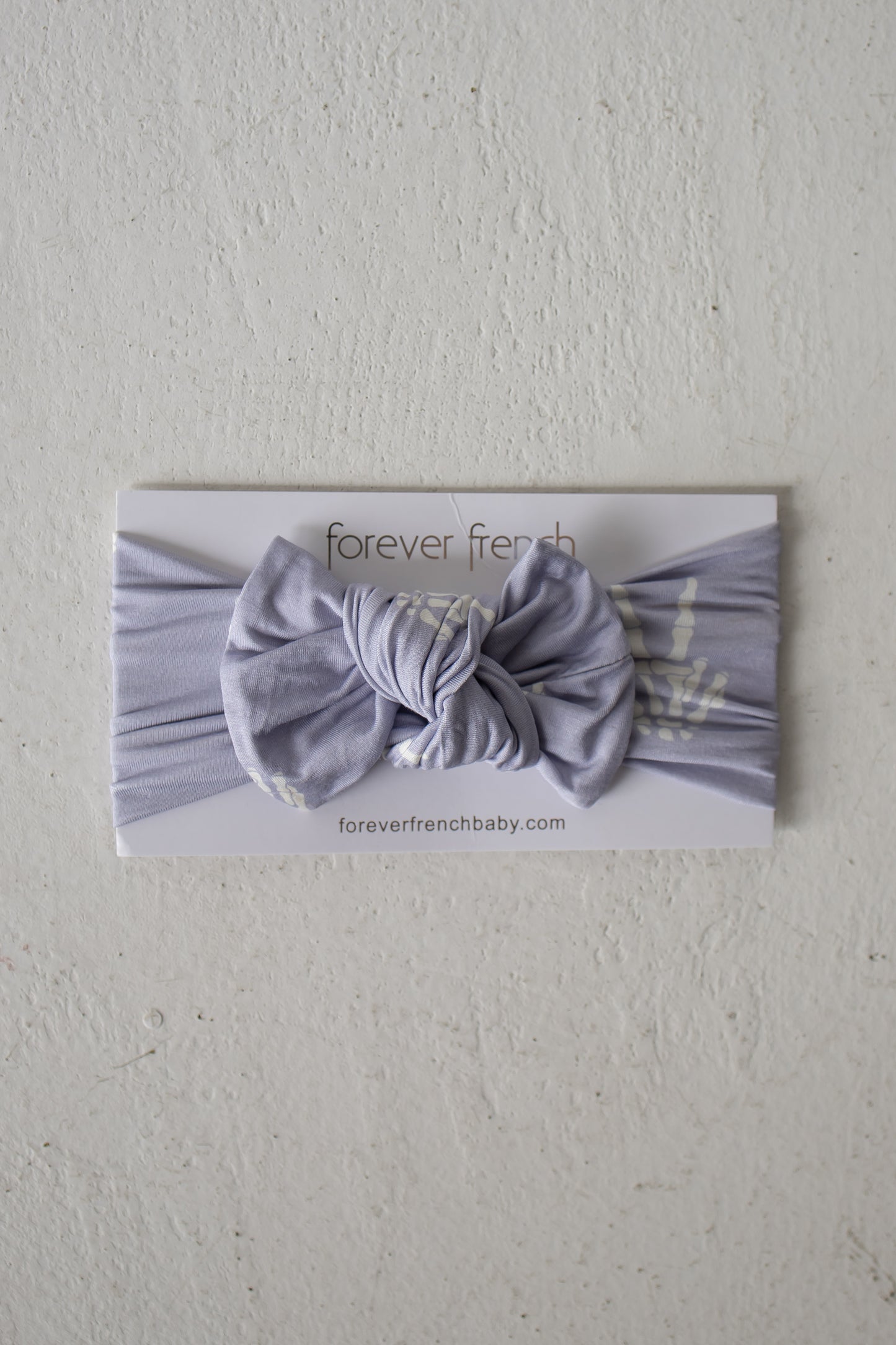 A Bamboo Head Wrap | Enchanted Skelly from forever french baby is displayed on a white card labeled “forever french baby” against a textured white background, showcasing this adorable bamboo head wrap that’s perfect for any little one.