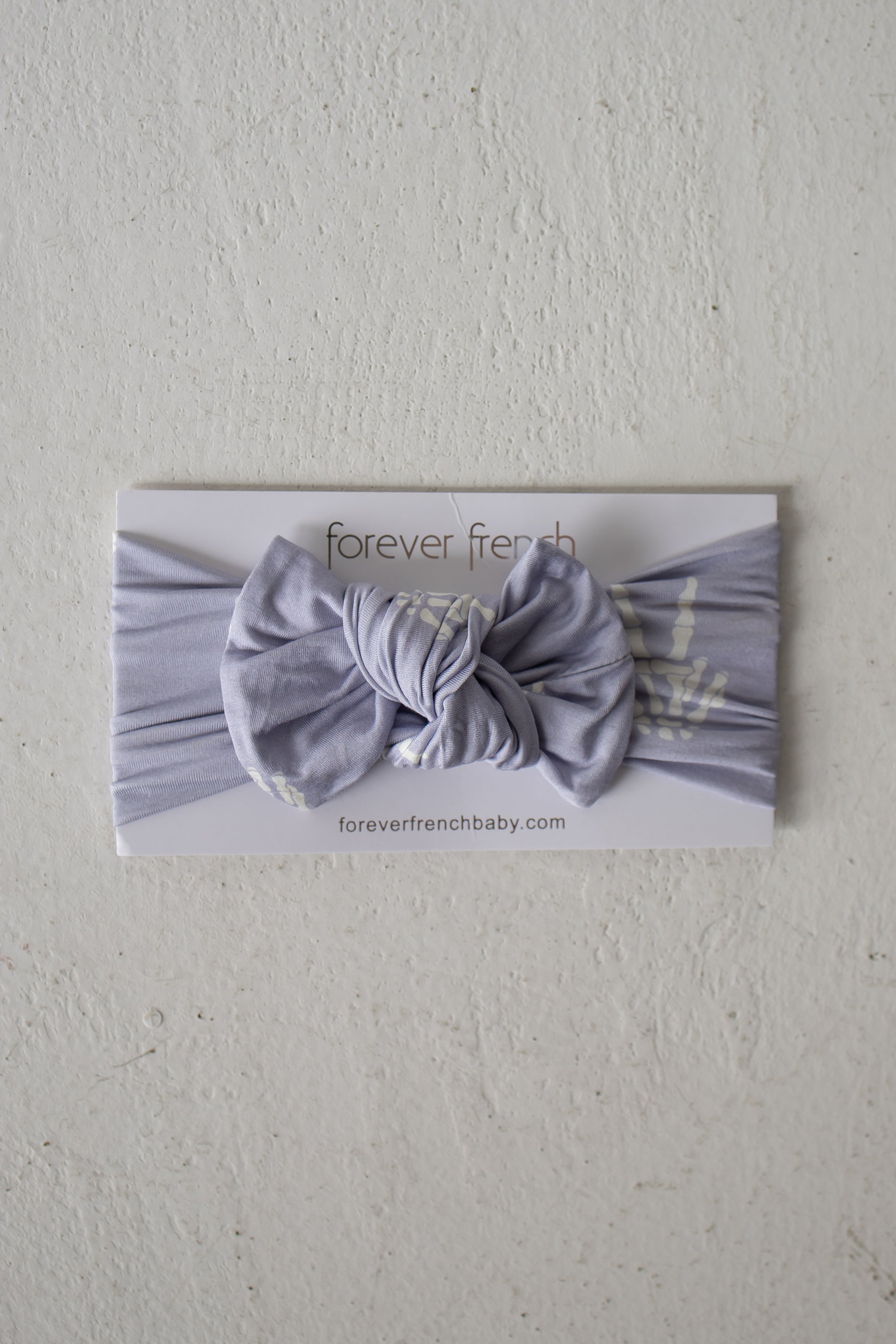A Bamboo Head Wrap | Enchanted Skelly from forever french baby is displayed on a white card labeled “forever french baby” against a textured white background, showcasing this adorable bamboo head wrap that’s perfect for any little one.