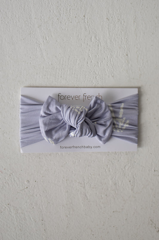 A Bamboo Head Wrap | Enchanted Skelly from forever french baby is displayed on a white card labeled “forever french baby” against a textured white background, showcasing this adorable bamboo head wrap that’s perfect for any little one.