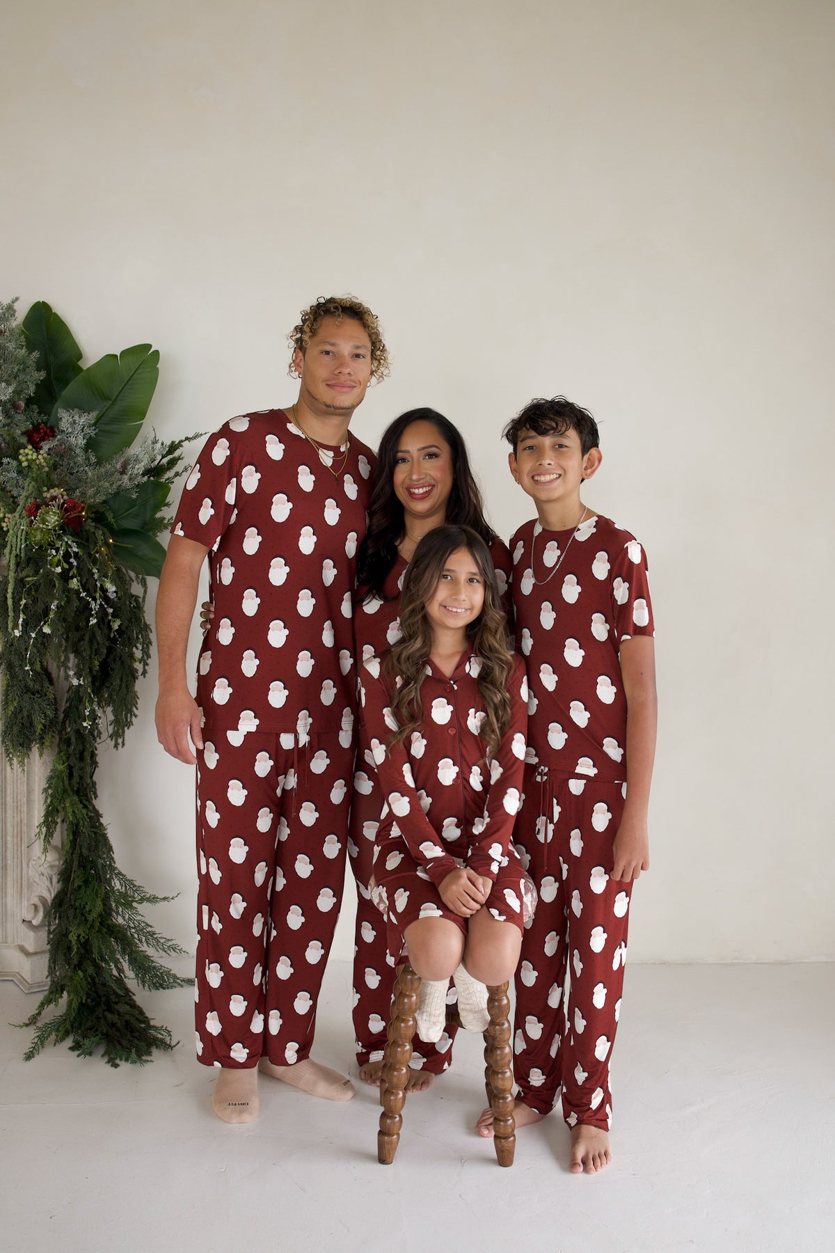 A family of four wears matching Men’s Short Sleeve Pajamas | Vintage Santa by forever french baby, featuring maroon short-sleeve bamboo sets with a white Santa Claus print.