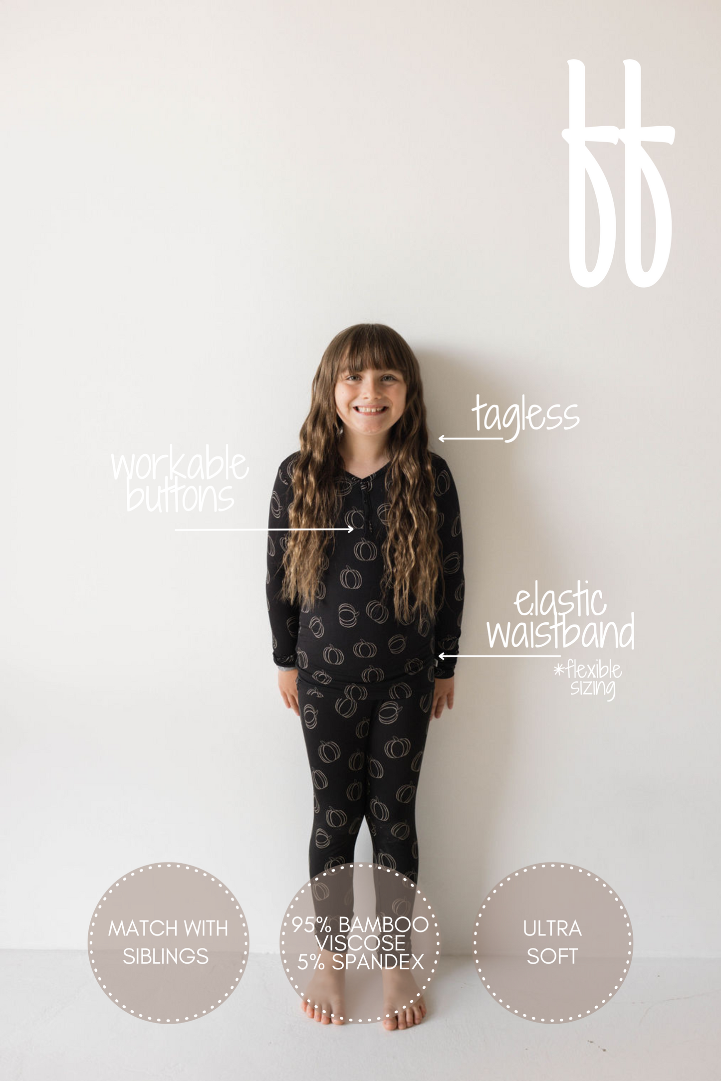 A young girl with long hair stands against a plain background wearing the Bamboo Two Piece Pajamas | Midnight Pumpkin from forever french baby, featuring breathable kids wear characteristics: workable buttons, tagless design, elastic waistband, 95% bamboo viscose and 5% spandex composition, ultra-soft texture, and the option to match with siblings.