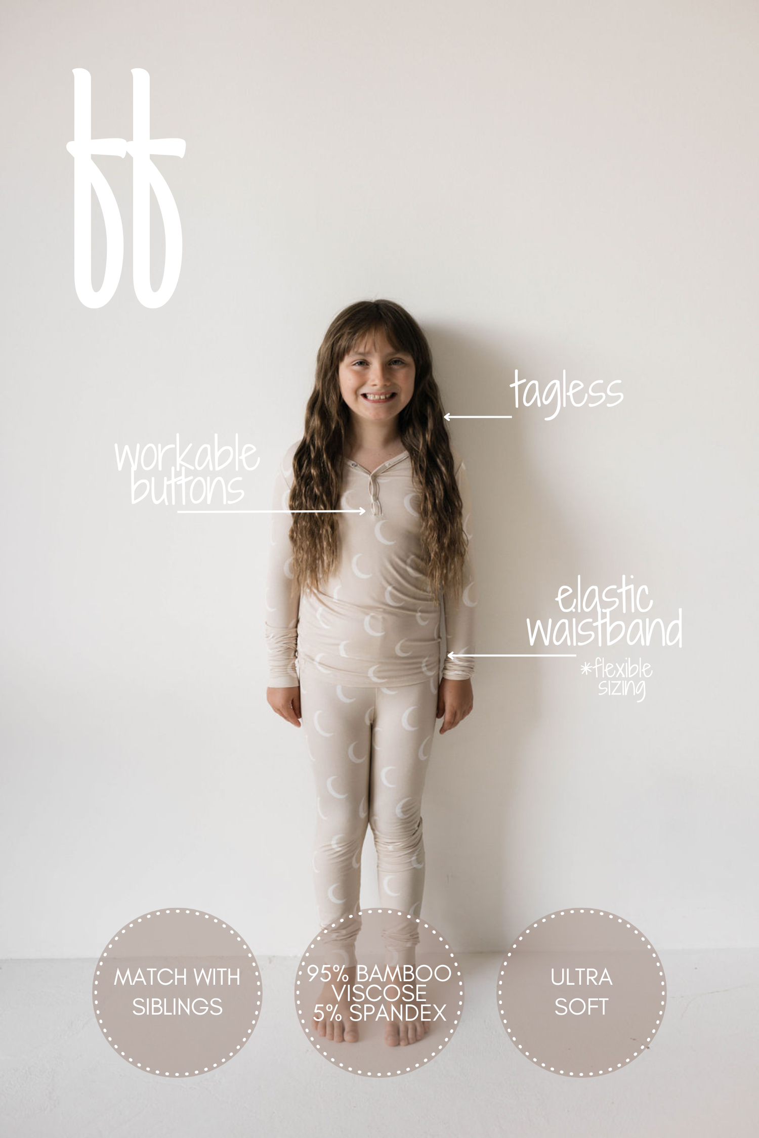 A child wearing the "Bamboo Two Piece Pajamas | Luna" by forever french baby, featuring a beige color with a moon pattern, stands against a white wall. Labels highlight features: "workable buttons," "tagless," "elastic waistband," "match with siblings," composed of "95% bamboo viscose, 5% spandex," and described as "ultra soft." These premium bamboo pajamas are also hypo-allergenic clothing.