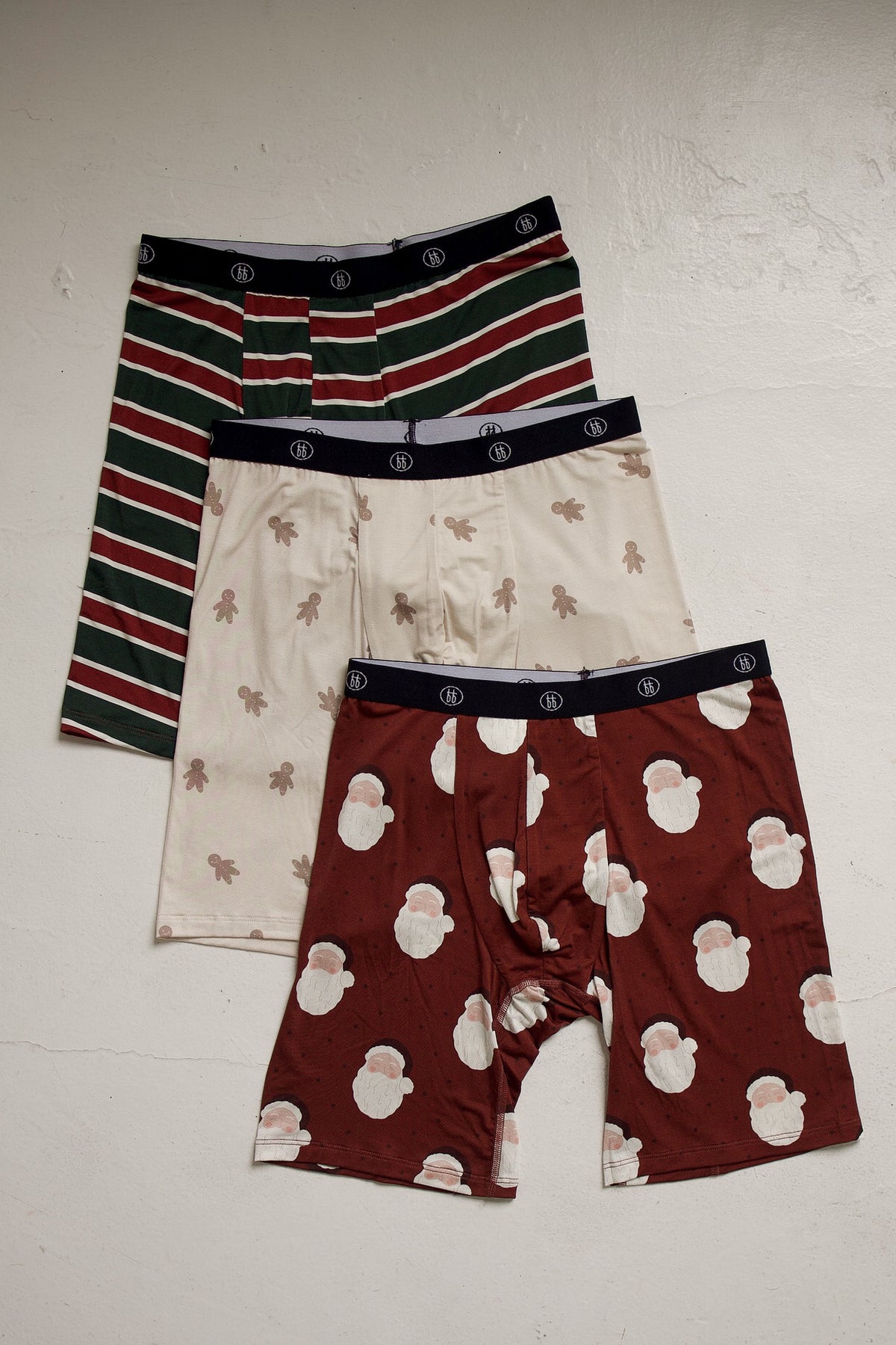 Three pairs of Men’s Bamboo Boxers (3 Pack) | Holiday ’26 from forever french baby, featuring one pair of red, green, and white striped, one gingerbread man print, and one Santa Claus print breathable bamboo boxer briefs.