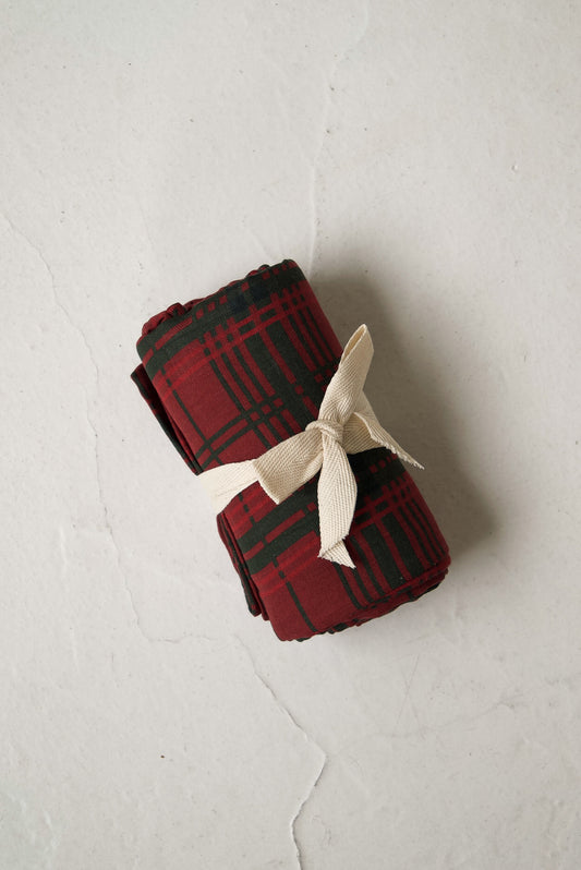 A rolled forever french baby Muslin Swaddle | Christmas Plaid tied with a cream ribbon.