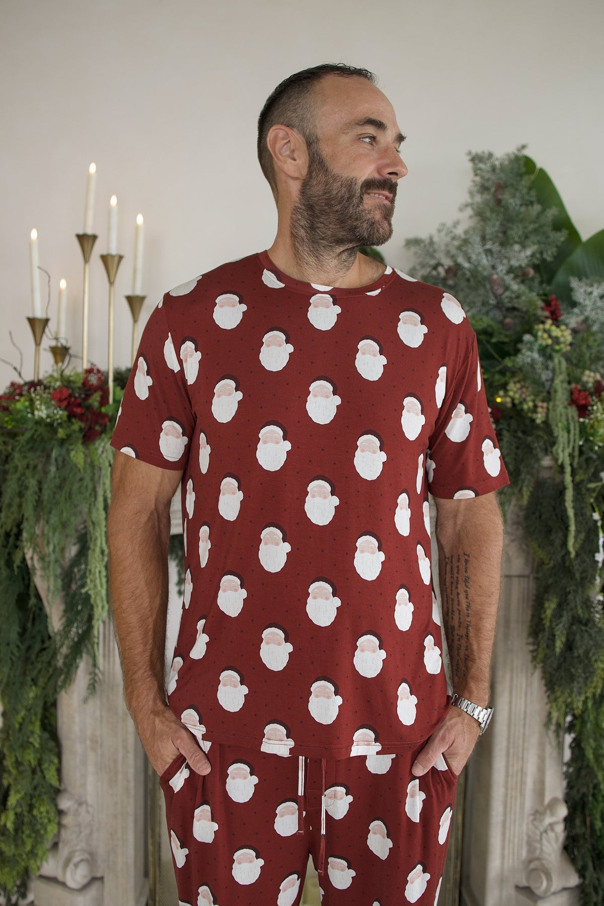 A man wearing a Men’s Short Sleeve Pajamas | Vintage Santa bamboo pajama set featuring a short-sleeve shirt and matching pants patterned with Santa Claus faces.