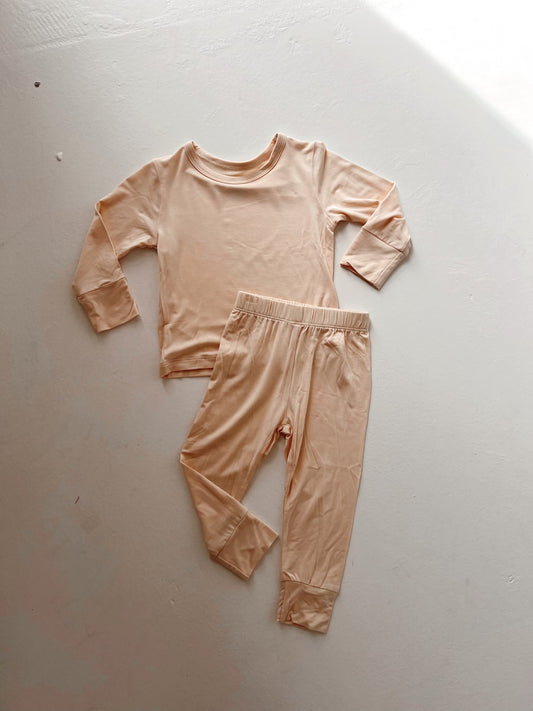 The Bamboo Two Piece Pajama in cream by forever french baby, showcased on a white surface, offers a breathable and soft experience. Made from bamboo fabric, it’s hypo-allergenic and perfect for comfort-seekers who appreciate smooth texture in sleepwear.