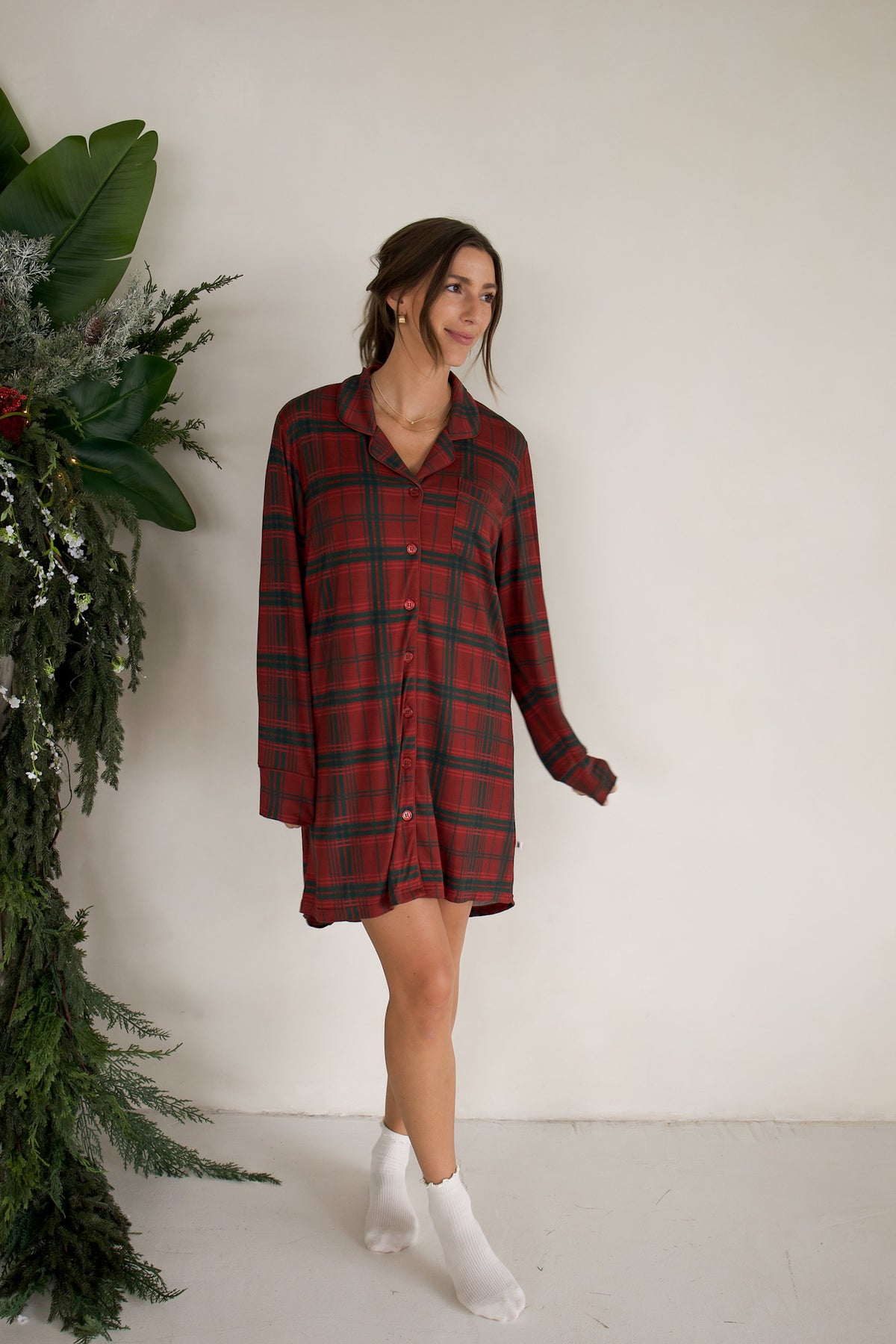 A woman wearing a Women’s Bamboo Sleeping Dress | Christmas Plaid long-sleeved button-down sleep shirt and white socks.