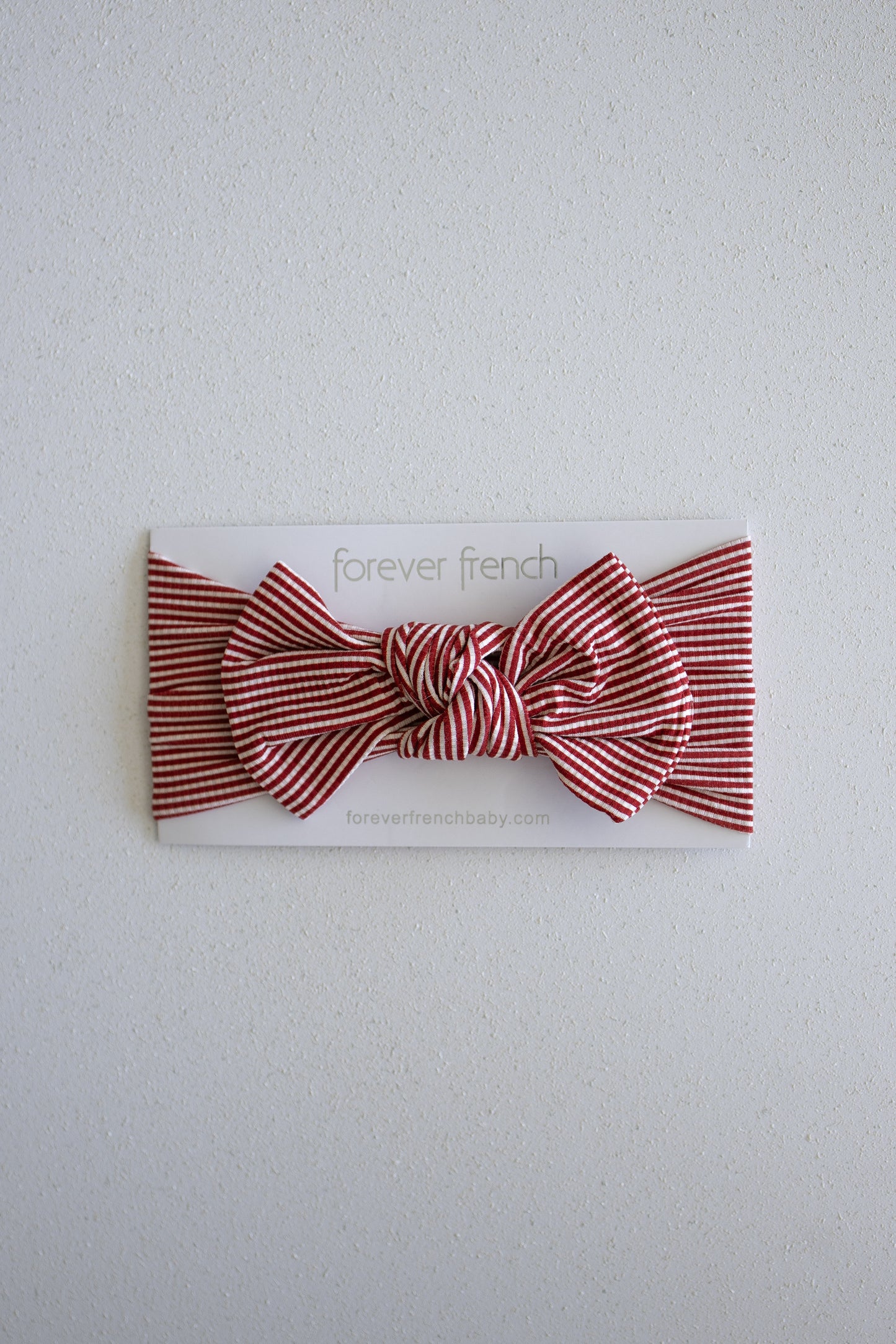 A Bamboo Head Wrap in Peppermint Stripe Ribbed from forever french baby is displayed on a white card labeled "forever french" against a light textured background.