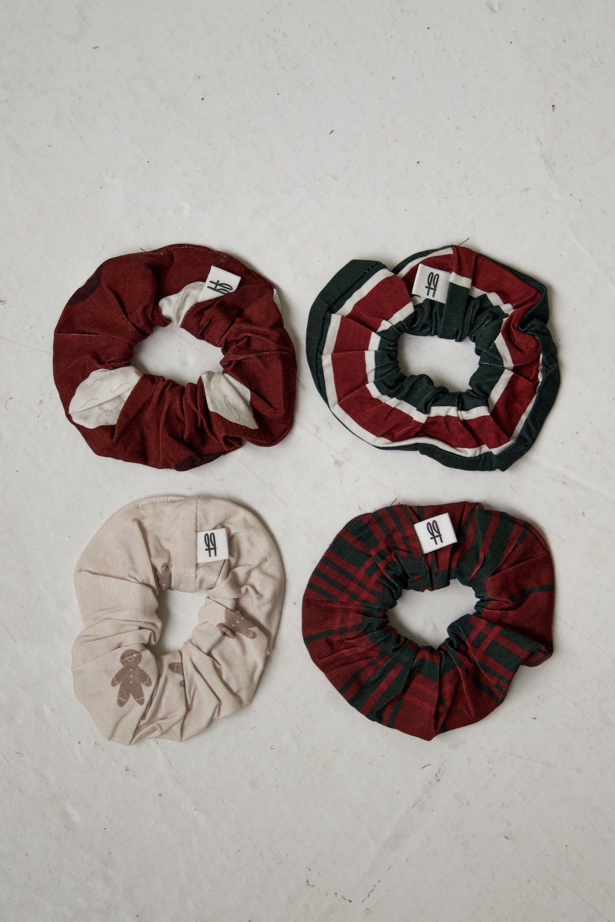 Four forever french baby Scrunchie | Christmas Plaid fabric hair scrunchies in red and white blocks, red and green stripes, cream with gingerbread men, and a Christmas plaid design.