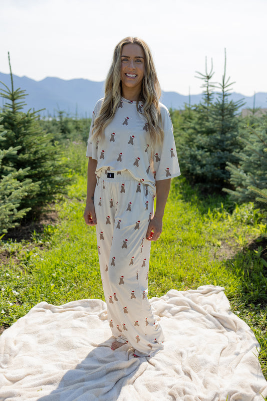 A woman stands smiling on a blanket outdoors among green trees, wearing the Women's Boxy Tee Lounge Set in Santa Teddy by forever french baby—a playful, breathable loungewear ensemble. Mountains are visible in the background under a bright, sunny sky.
