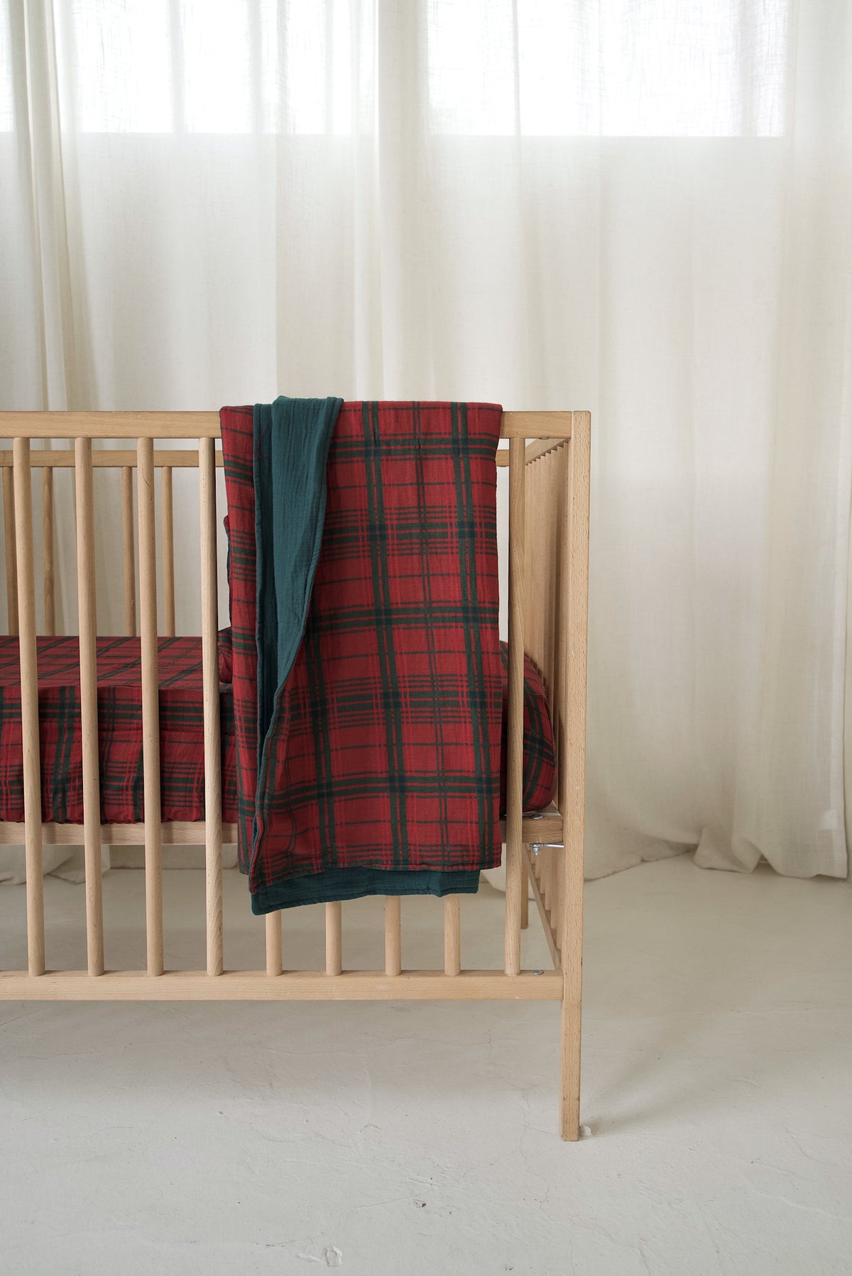 Forever French Baby Muslin Quilt | Christmas Plaid draped over the side of a wooden crib.
