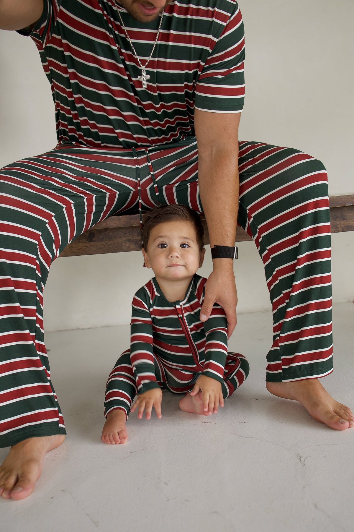 A baby and an adult sit together wearing matching Holiday Stripe Bamboo Zip Pajamas by forever french baby.