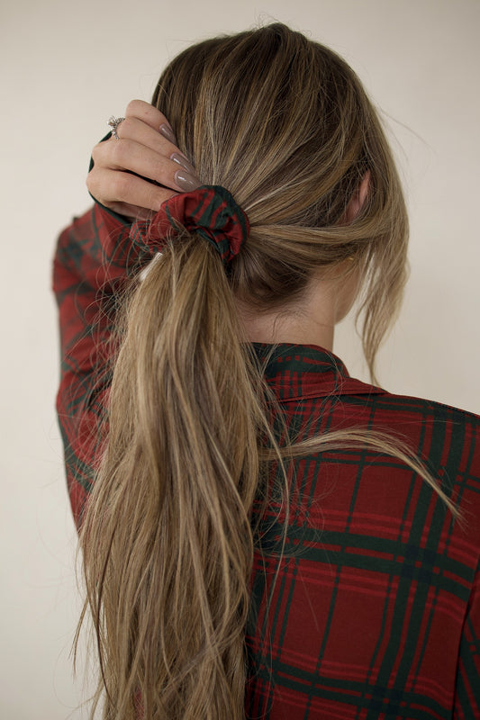 View from behind of a person in a low ponytail with a red and green Christmas Plaid | Scrunchie by forever french baby, wearing a matching plaid top.