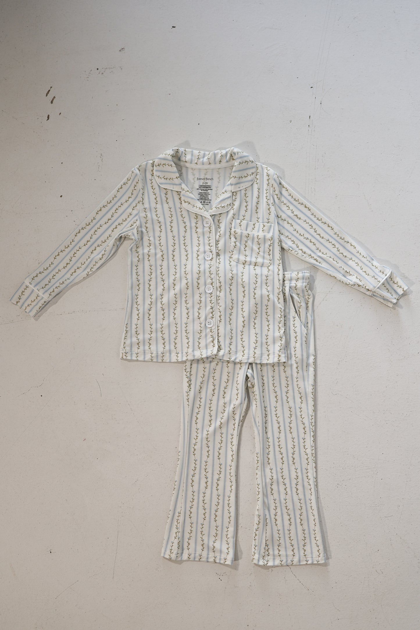 The forever french baby Girl’s Bamboo Button Up Lounge Set | Dainty Vines features soft, hypo-allergenic children’s pajamas with long sleeves and pants in white with green and gold vertical stripes, shown flat on a white surface.