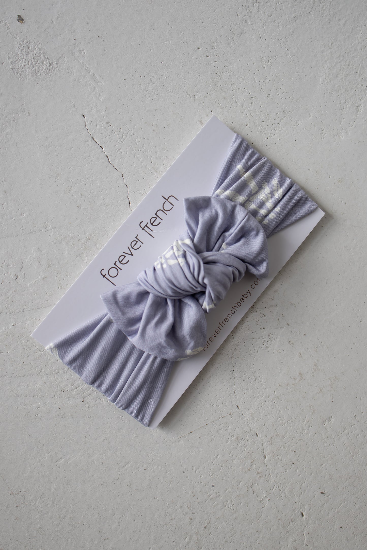 A Bamboo Head Wrap | Enchanted Skelly from forever french baby is displayed on a branded white card, set against a light textured surface.