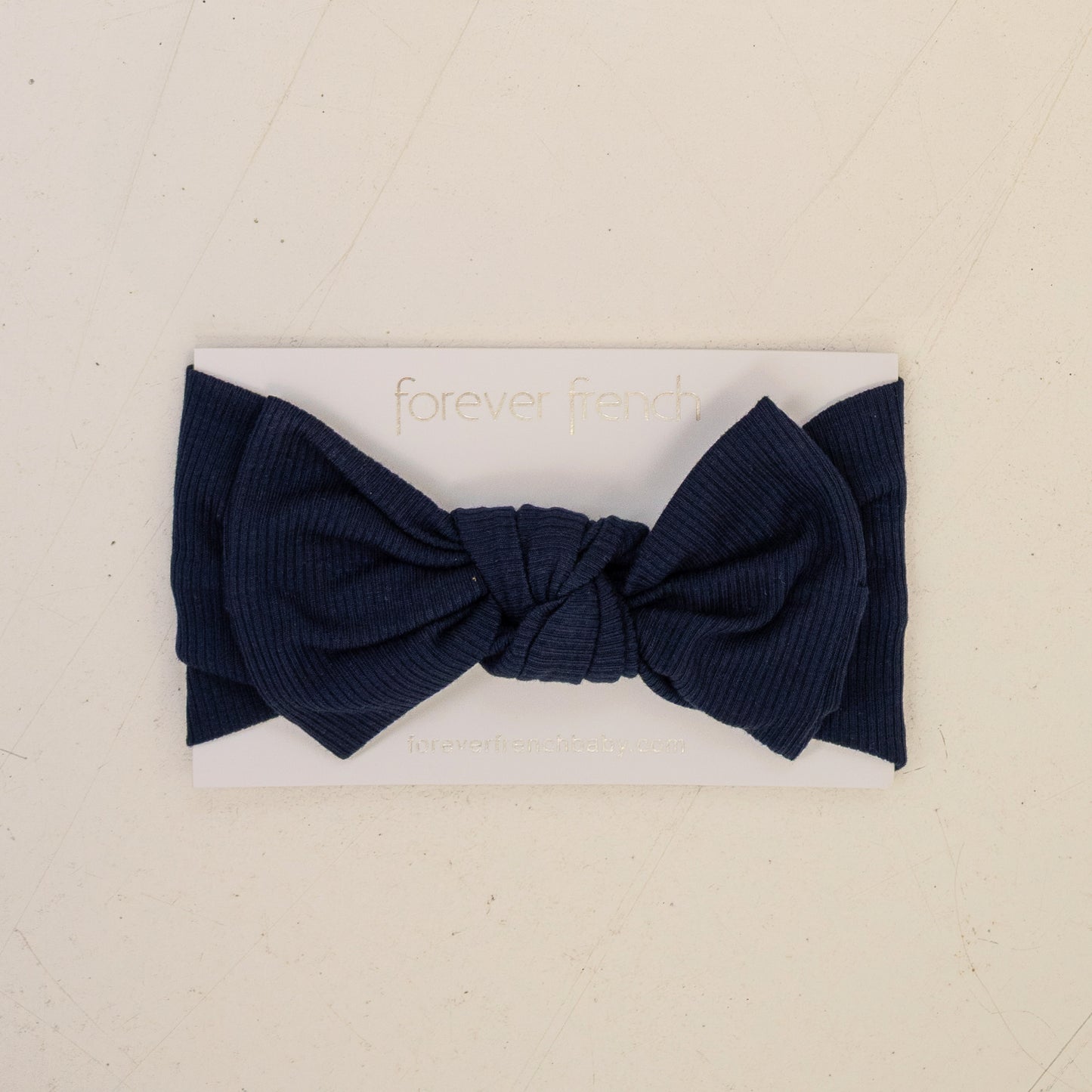 The Bamboo Head Wrap | Blueberry Ribbed by forever french baby features a large navy ribbed bow, shown on a white branded card against a light beige background.