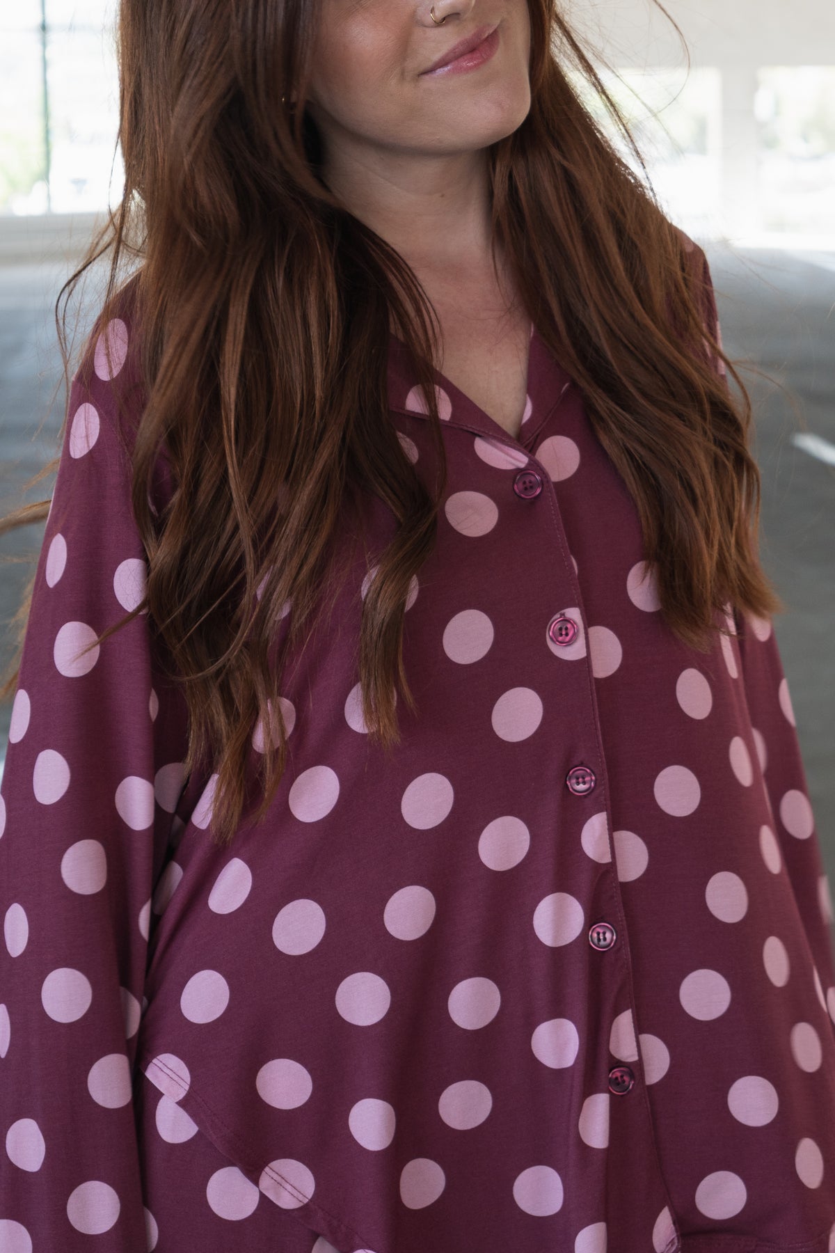 A woman with long brown hair wears the forever french baby Women’s Bamboo Button Up Lounge Set in Heather Rose Dot, standing in a well-lit indoor location.