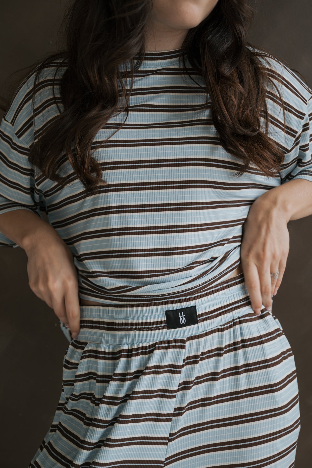 A person wearing a breathable, blue and brown striped ribbed Women’s Boxy Tee Lounge Set | Dean by forever french baby, featuring a boxy short-sleeved t-shirt and matching shorts with a branded waistband label.