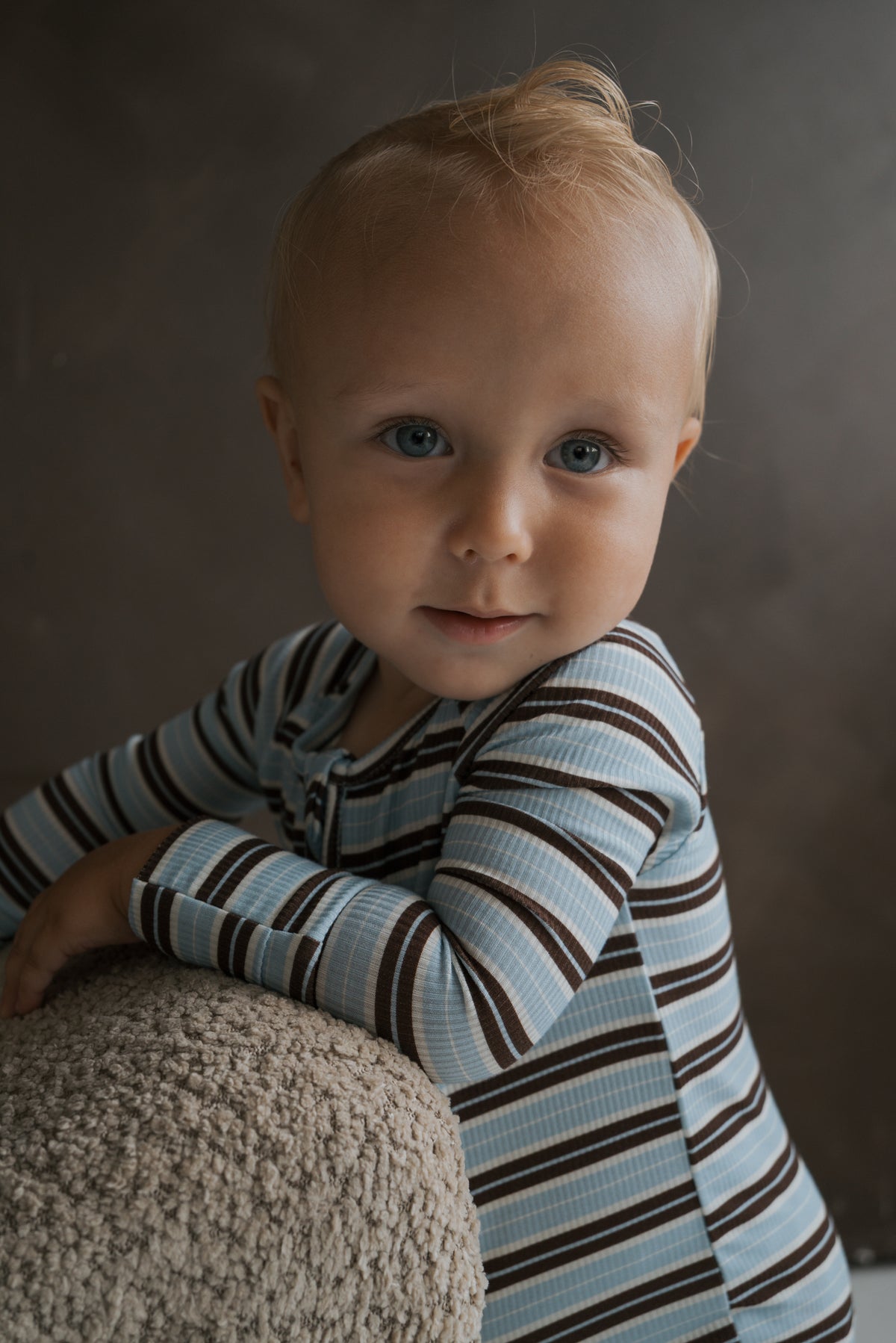 A toddler wearing blue and brown striped Bamboo Zip Pajamas | Dean with long sleeves and a zipper.